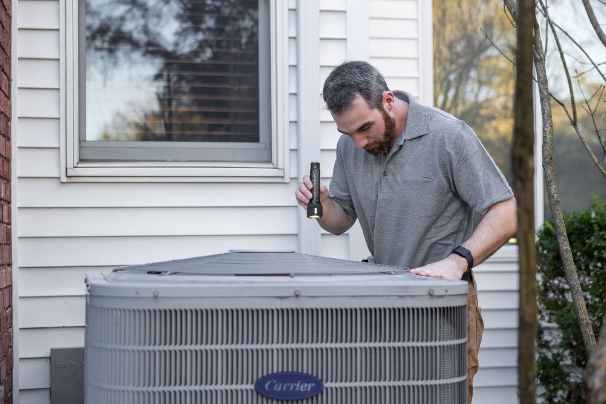 Engineer inspecting an outdoor air conditioning condenser unit