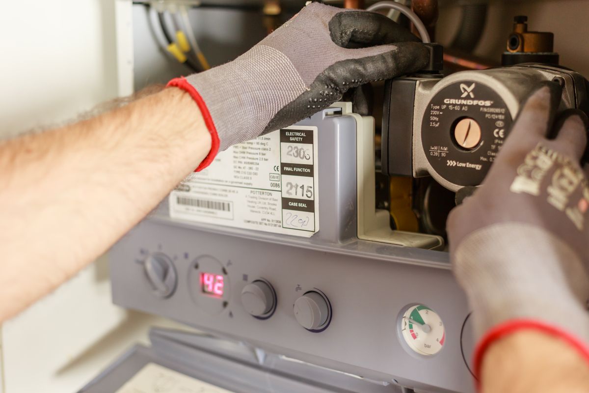 Gas Safe engineer working inside an open combi boiler