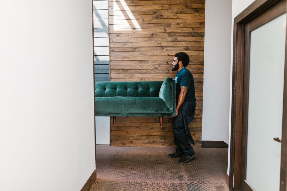 Mover carrying a sofa into a home during a house move