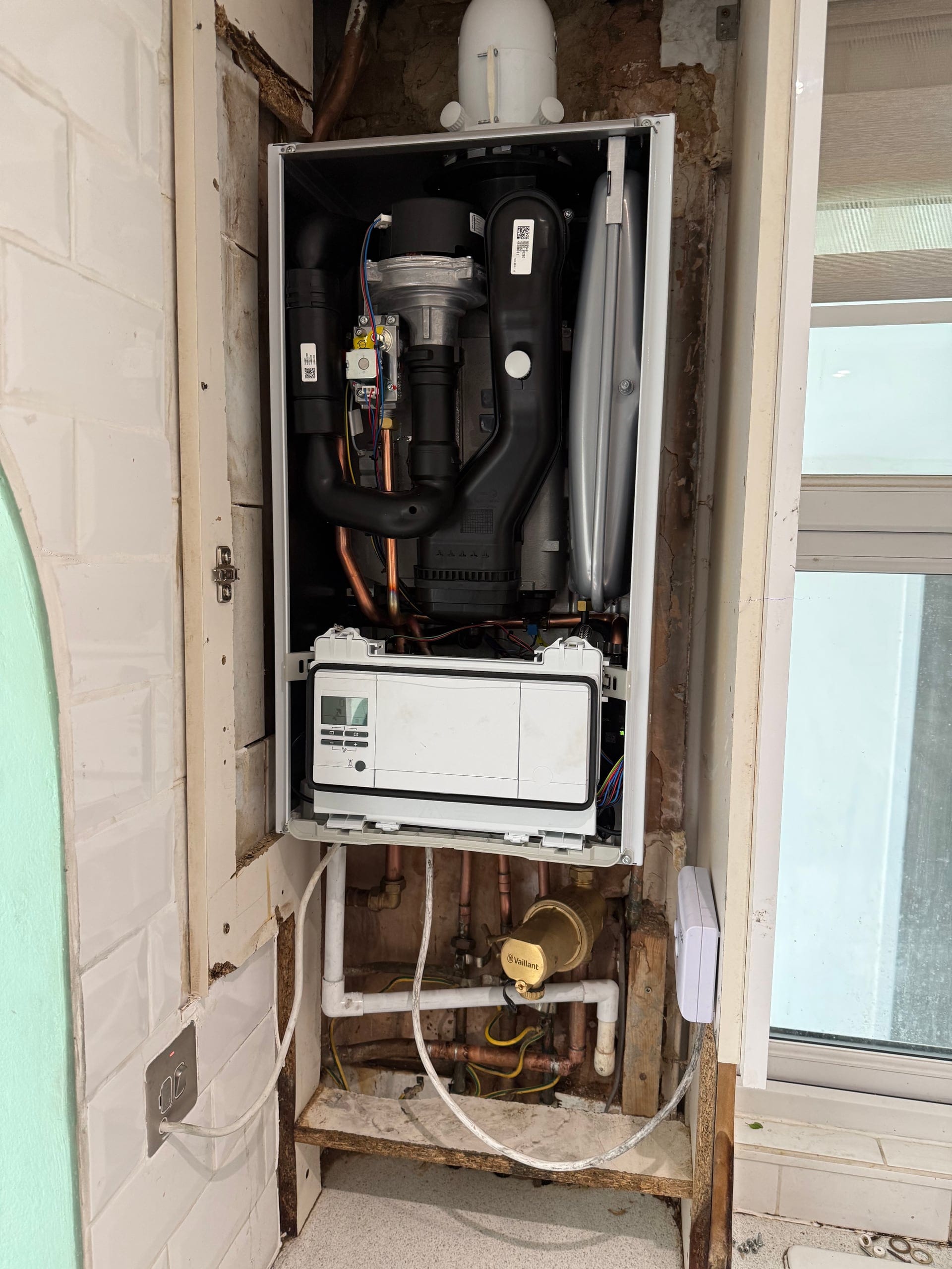 Boiler opened up for servicing, showing the control board, gas cock and pipework