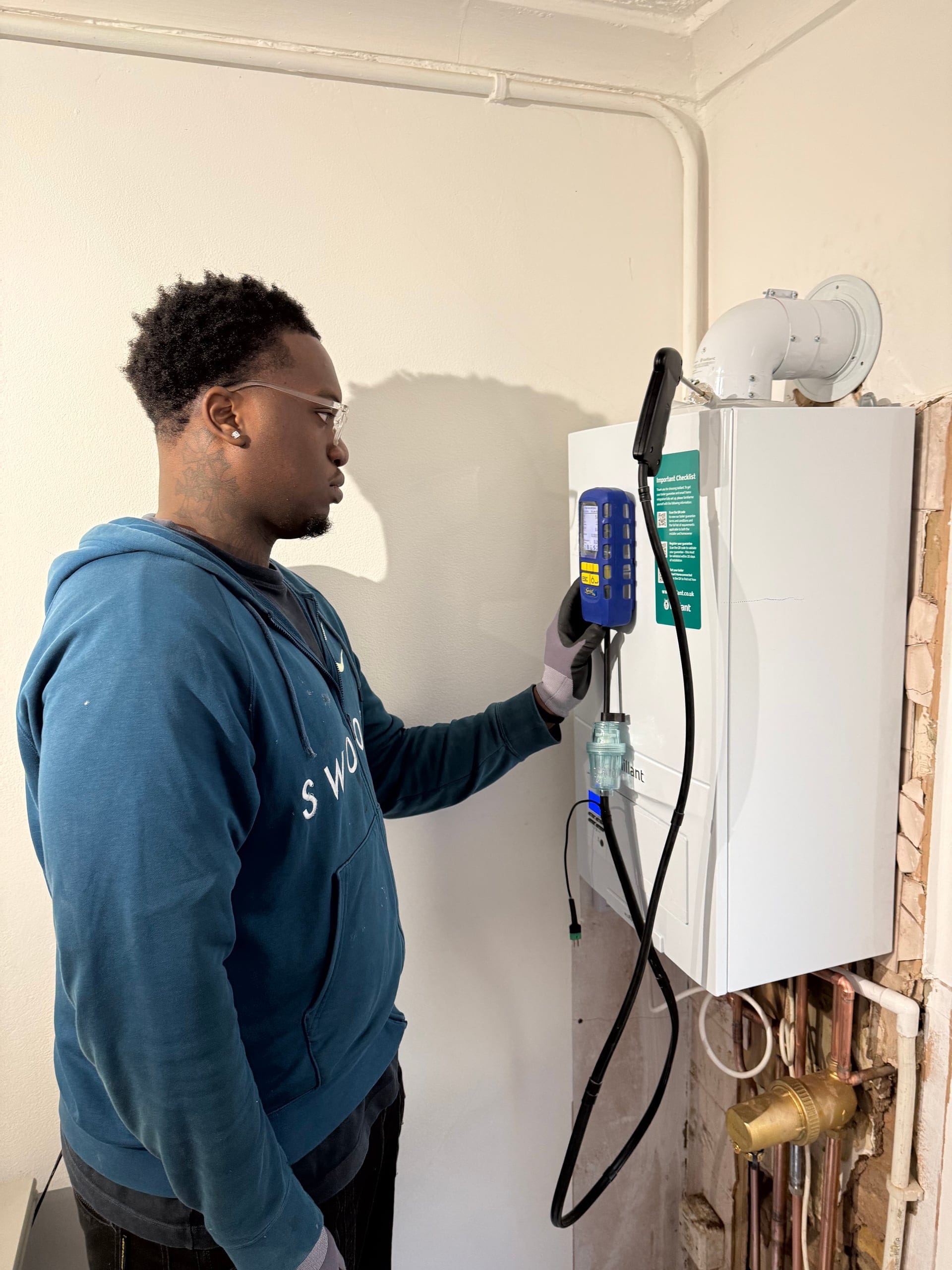 Gas Safe engineer testing at the boiler while wiring in smart heating controls