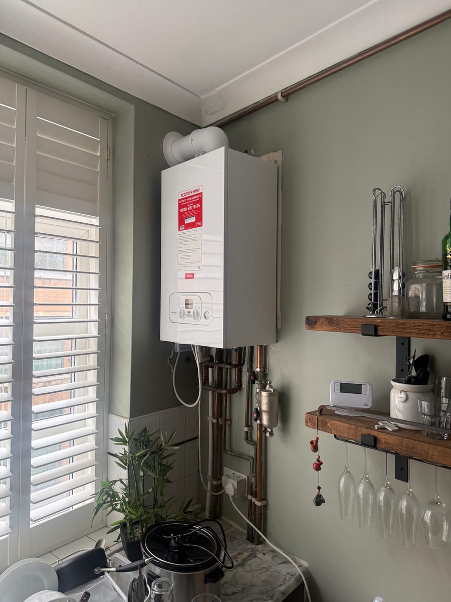 Combi boiler installed in a finished kitchen with shutters, seen from across the room