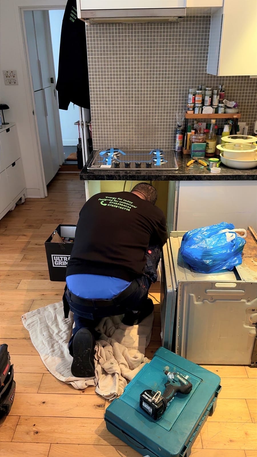 Engineer working under a kitchen worktop on a London job
