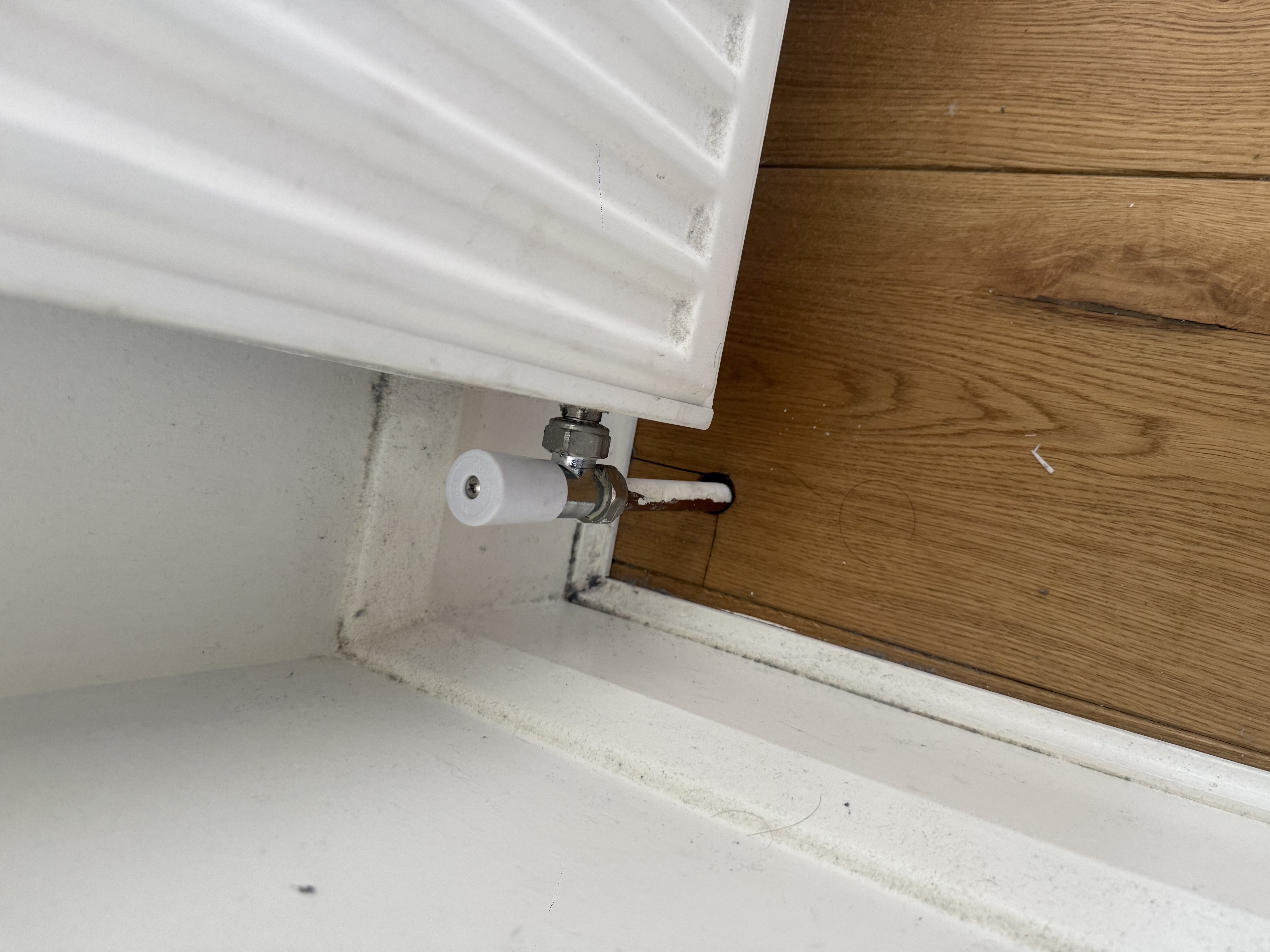 Radiator valve and pipe connection beside a wall